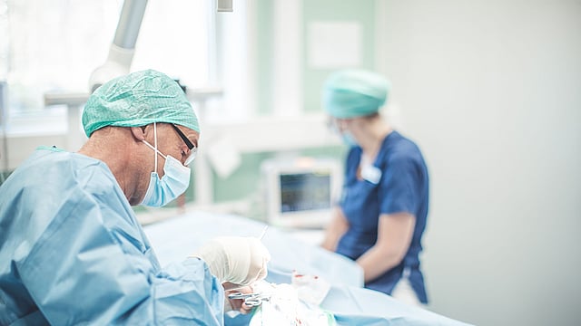 Operationssalen där två veterinärer jobbar i skyddskläder.