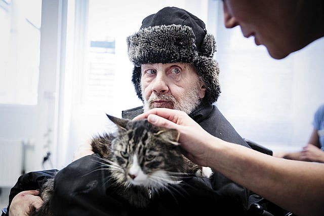 En person i en hatt och pälshatt som håller en katt.